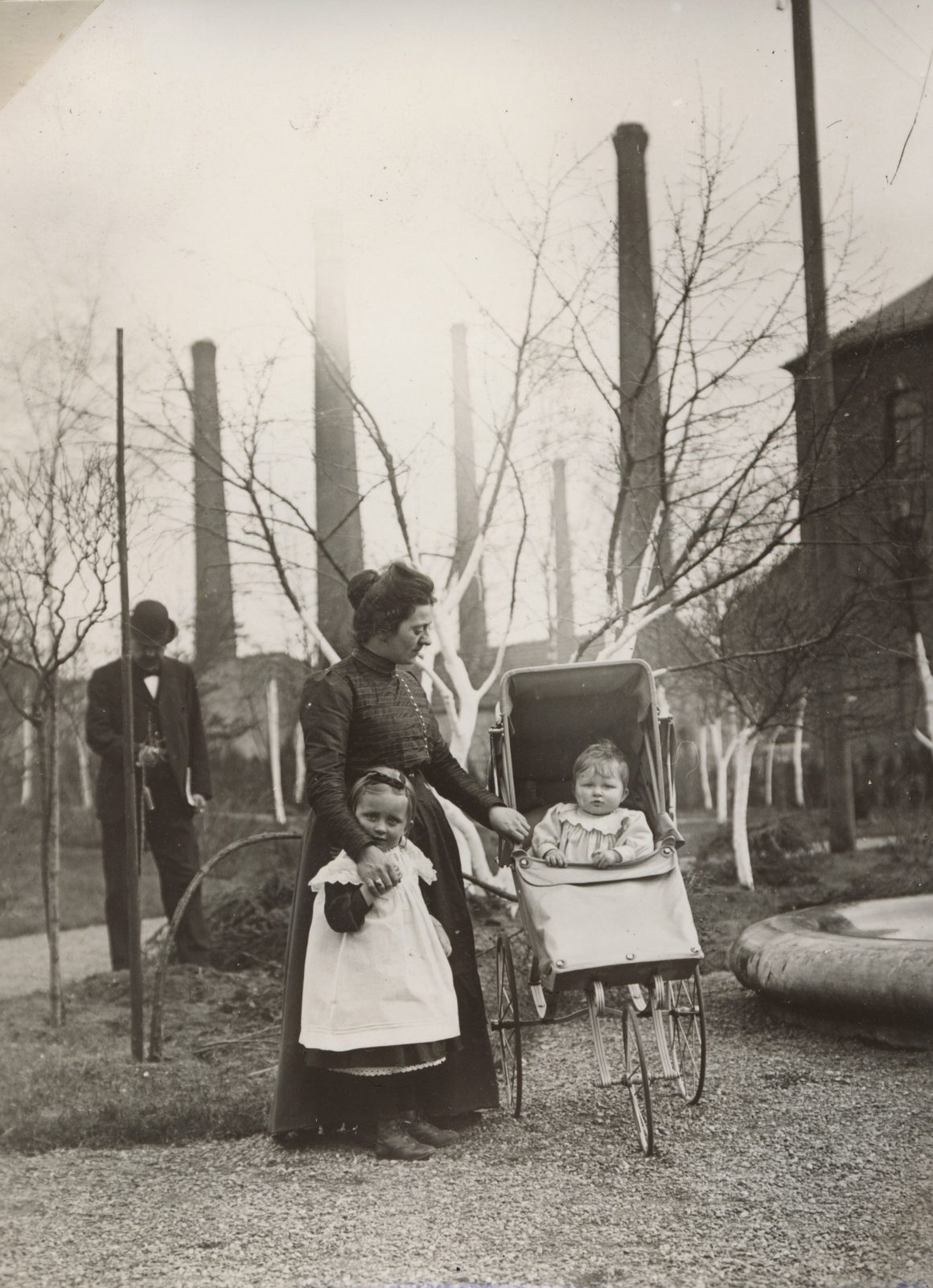 Blick vom Brunnen zur Fabrik, wahrscheinlich Babette (Frau von Erhard I) mit Else und Brunhilde um 1900, im Hintergrund Erhard?