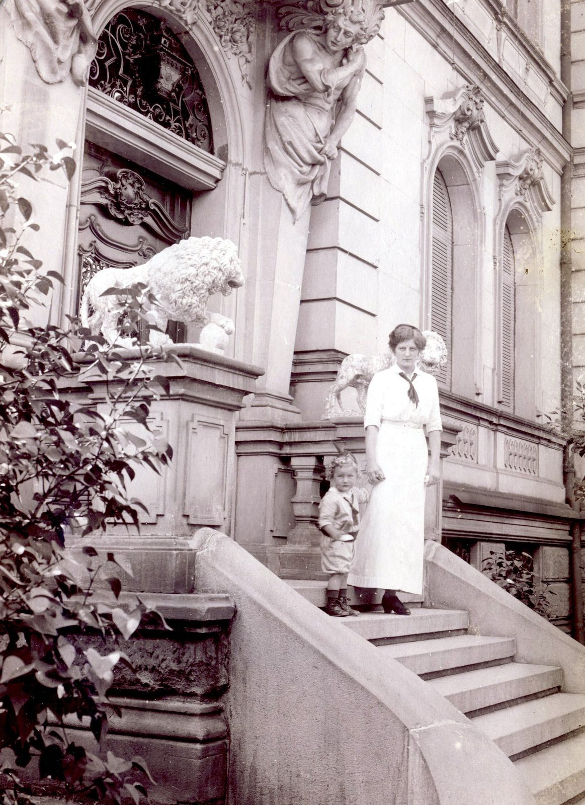 Elsa steht mit Sohn Werner am Eingang. Löwen säumen den Eingang. 1913